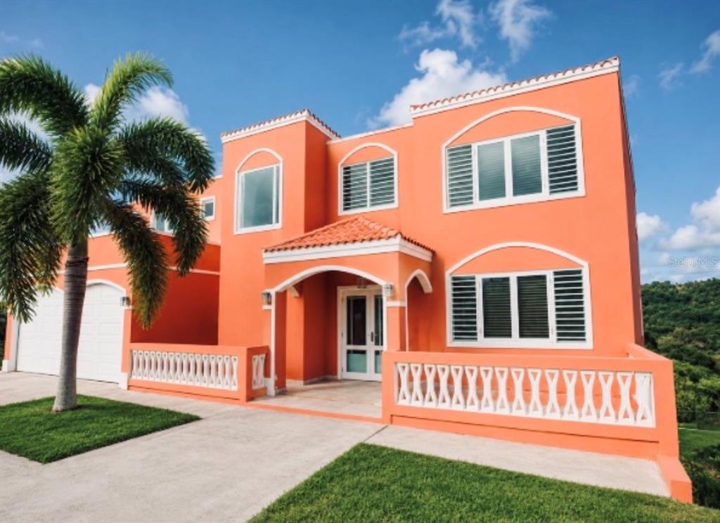 A two-story orange house with a palm tree, white railings, and a tiled roof — 22 MANSIONES DE TERRALINDA, LUQUILLO, PR