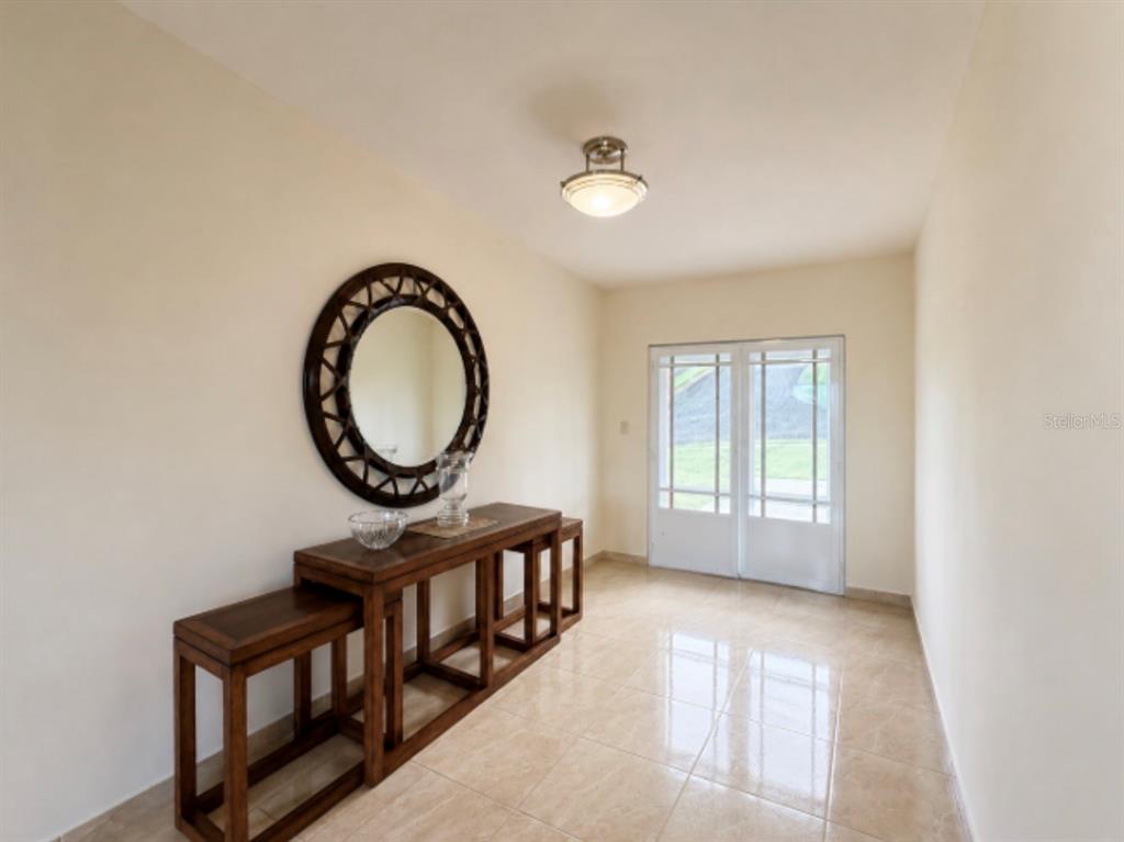 An entryway features a console table, a round mirror, tile flooring, and glass double doors — 22 MANSIONES DE TERRALINDA, LUQUILLO, PR
