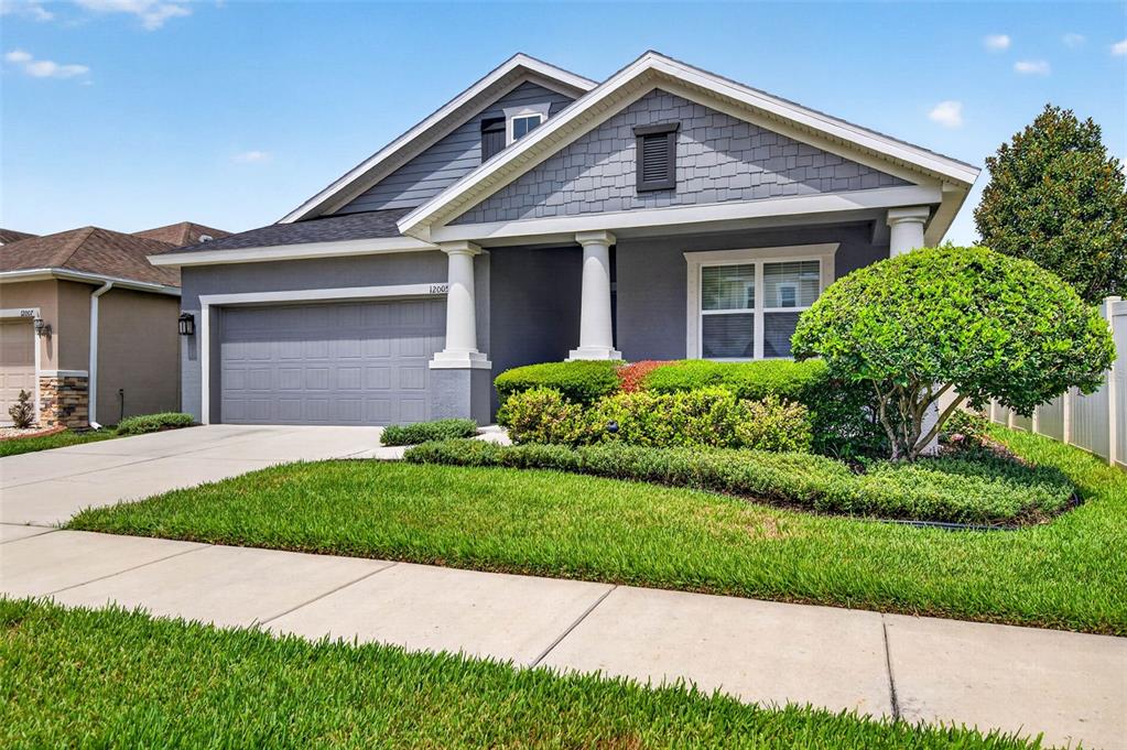 A single-story house with a gray exterior, a two-car garage, and a landscaped front yard — 12005 RAMBLING STREAM DRIVE, RIVERVIEW, FL