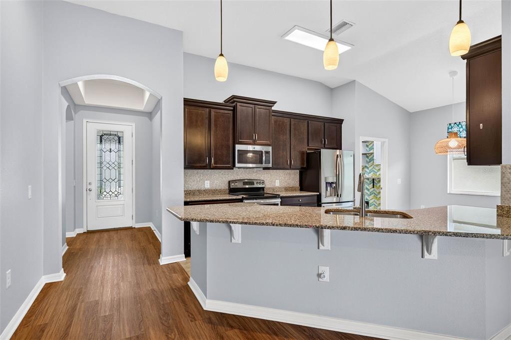 A kitchen with dark wood cabinets, granite countertops, and a breakfast bar island — 12005 RAMBLING STREAM DRIVE, RIVERVIEW, FL
