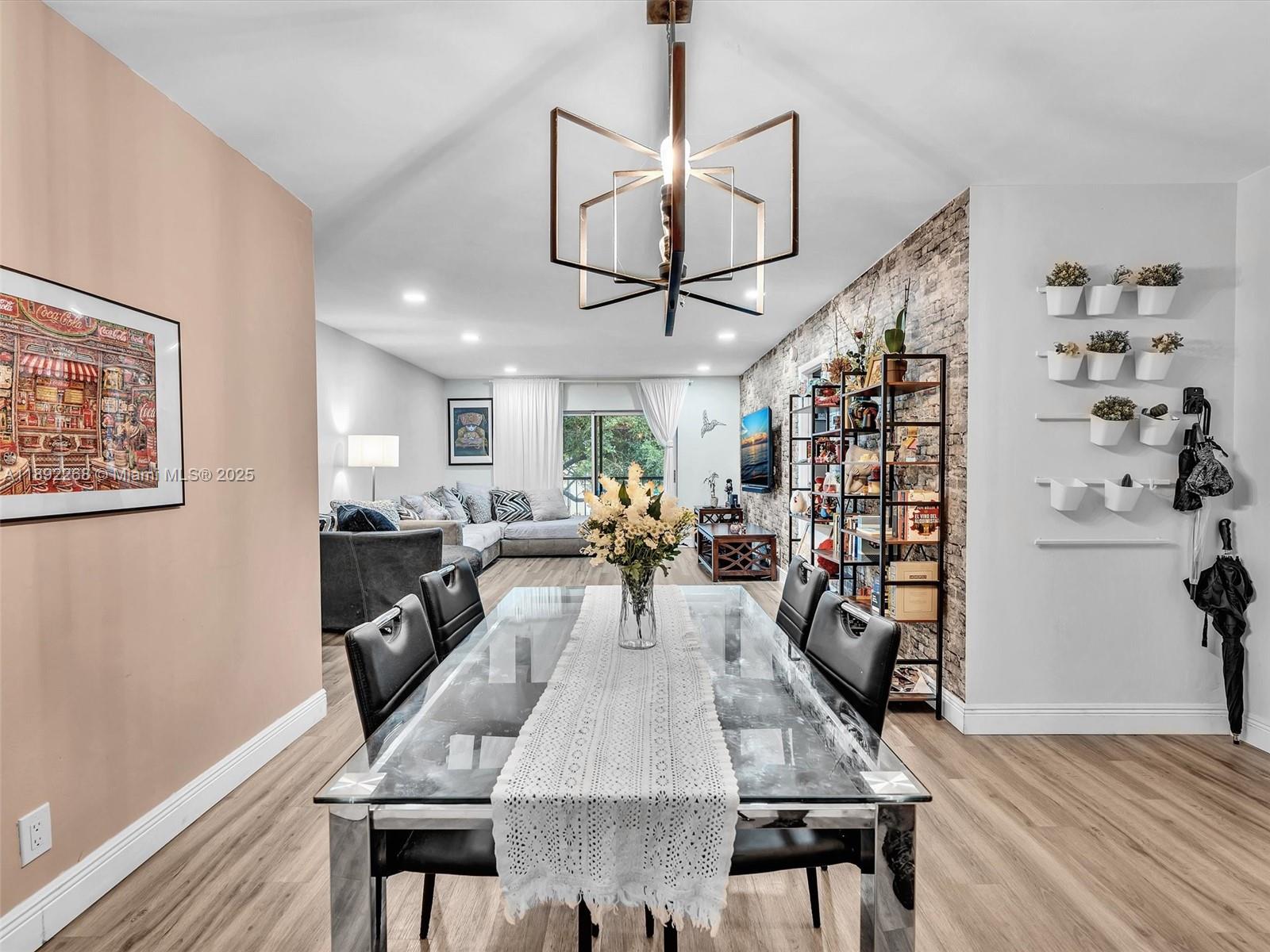 A dining area with a glass table and chandelier opens into a living room — 6061 N Falls Cir Dr # 407, Lauderhill FL 33319, LAUDERHILL, FL