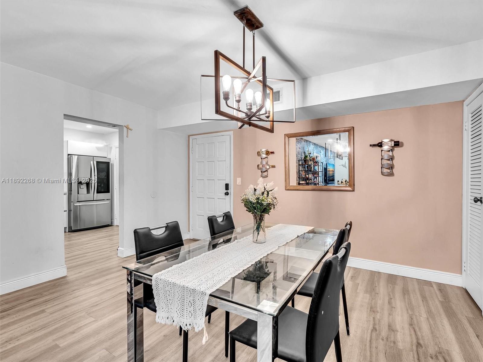 A dining room features a glass-top table, black chairs, and a modern chandelier — 6061 N Falls Cir Dr # 407, Lauderhill FL 33319, LAUDERHILL, FL