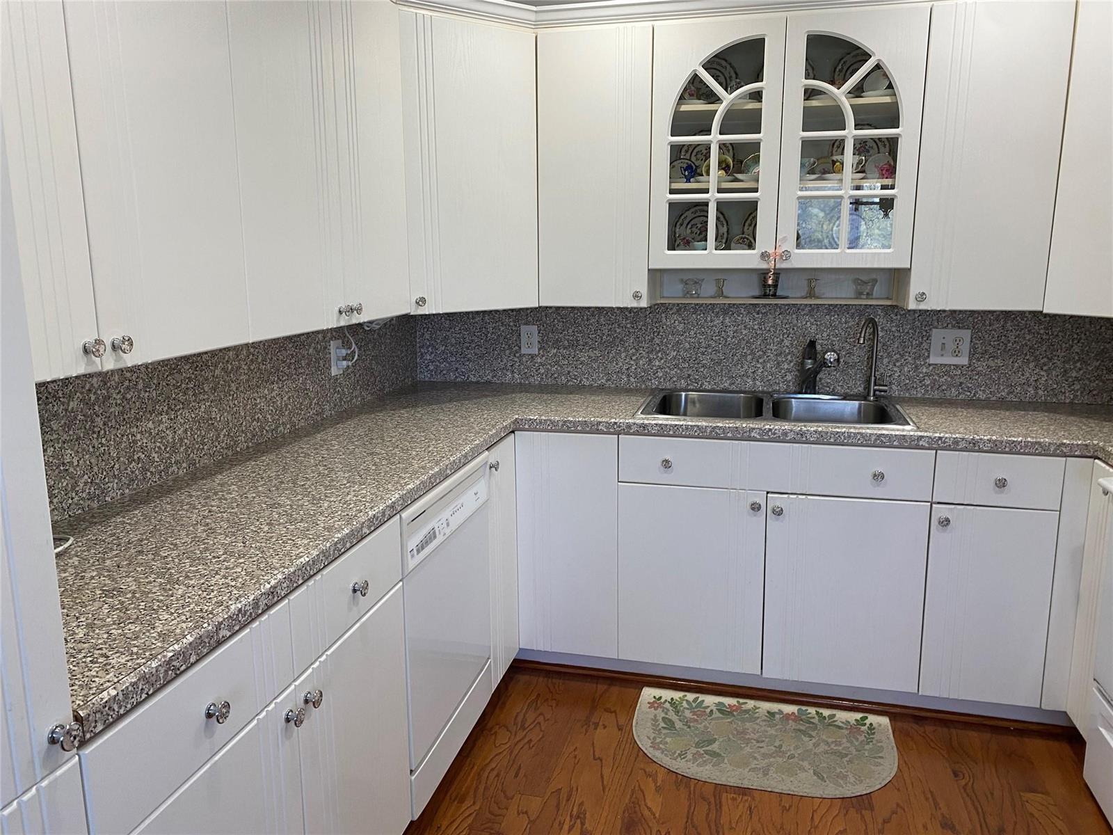 A kitchen features white cabinets, granite countertops, a double sink, and hardwood flooring — 4011 Upminster J # 4011, Deerfield Beach FL 33442, DEERFIELD BEACH, FL