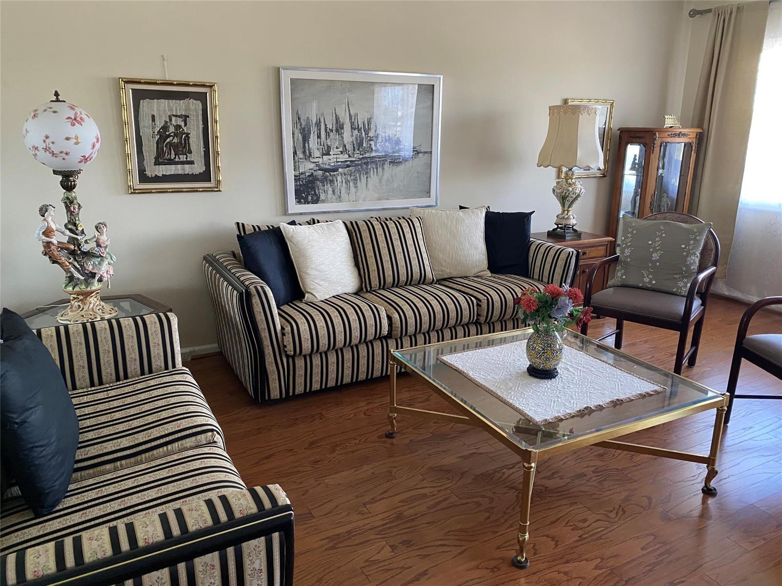 A living room features striped sofas, a glass coffee table, and framed wall art — 4011 Upminster J # 4011, Deerfield Beach FL 33442, DEERFIELD BEACH, FL