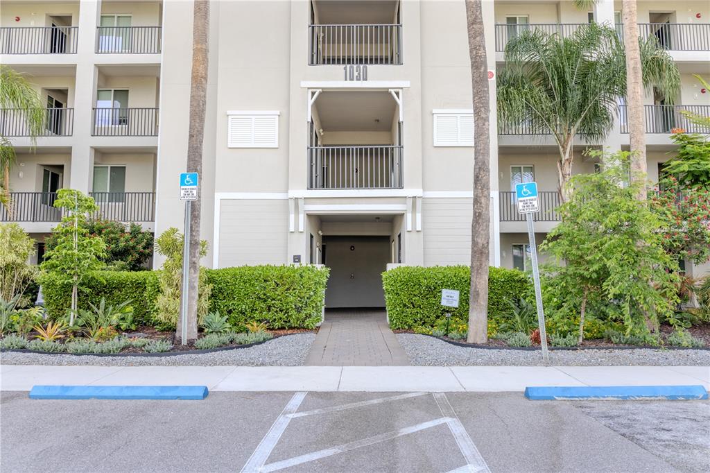 A multi-story apartment building exterior features a central entrance, balconies, and two handicap parking spaces — 1030 TIDEWATER SHORES LOOP UNIT 104, BRADENTON, FL