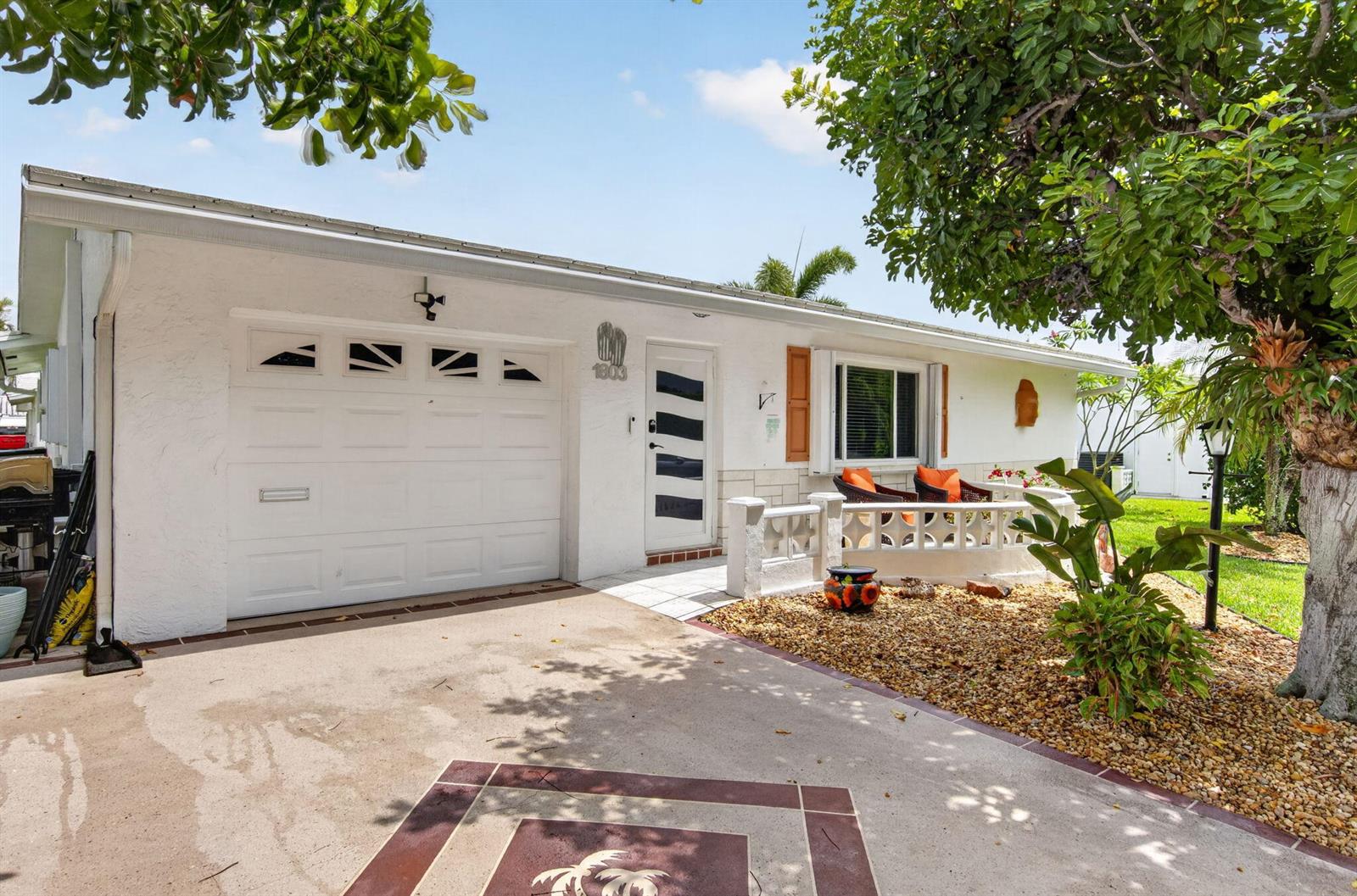 A white single-story house features a garage, a front porch, and a paved driveway — 1803 SW 22nd Way, Boynton Beach FL 33426, BOYNTON BEACH, FL