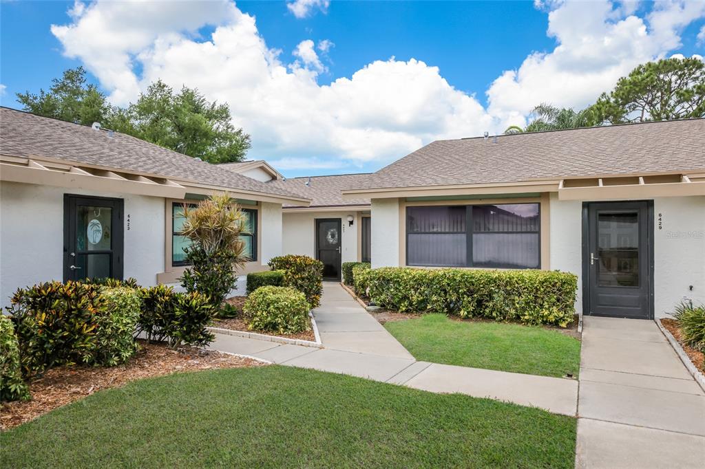 A view of the exterior of two adjacent residential units with walkways and landscaping — 6427 HERITAGE LANE UNIT 6427, BRADENTON, FL