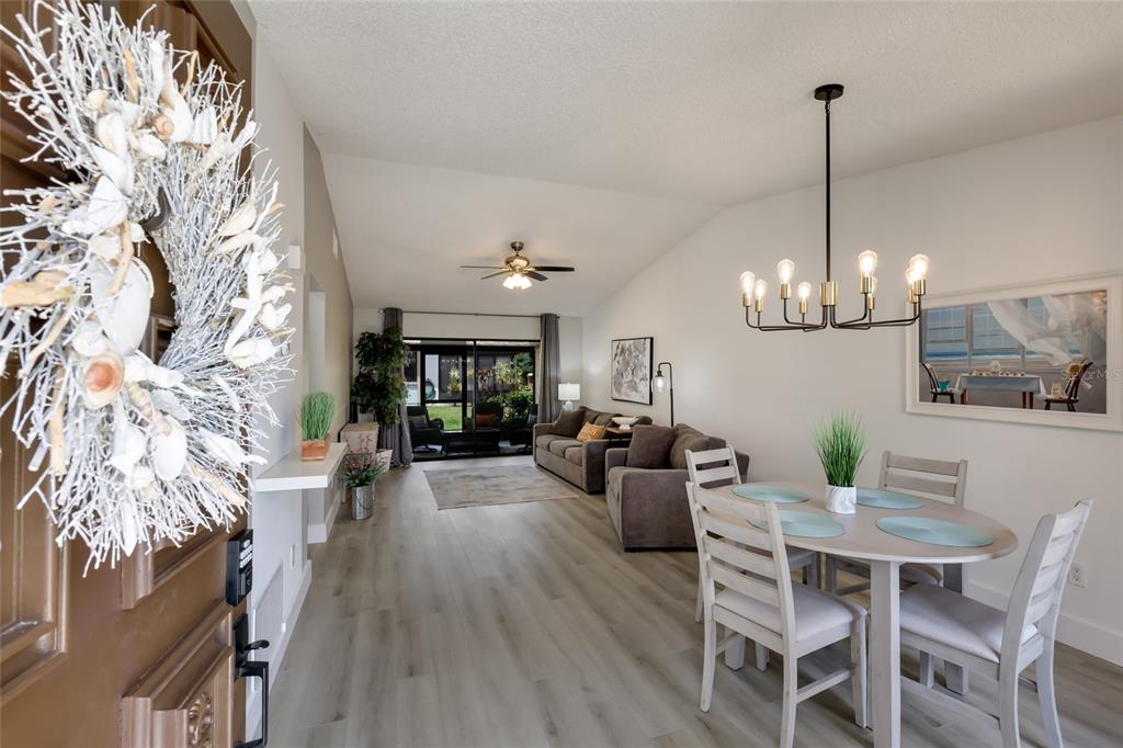 An open-concept living and dining area features light wood flooring, a chandelier, and sliding doors — 6427 HERITAGE LANE UNIT 6427, BRADENTON, FL