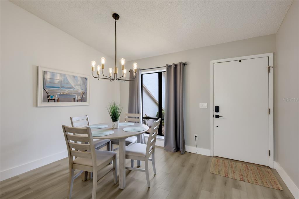 A dining area features a round table, four chairs, a chandelier, and a white door — 6427 HERITAGE LANE UNIT 6427, BRADENTON, FL