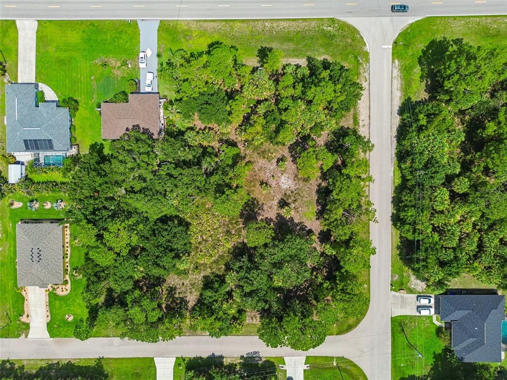 An aerial view shows a vacant, wooded residential lot situated between two existing houses — 14 S CHAMBERLAIN BOULEVARD, NORTH PORT, FL