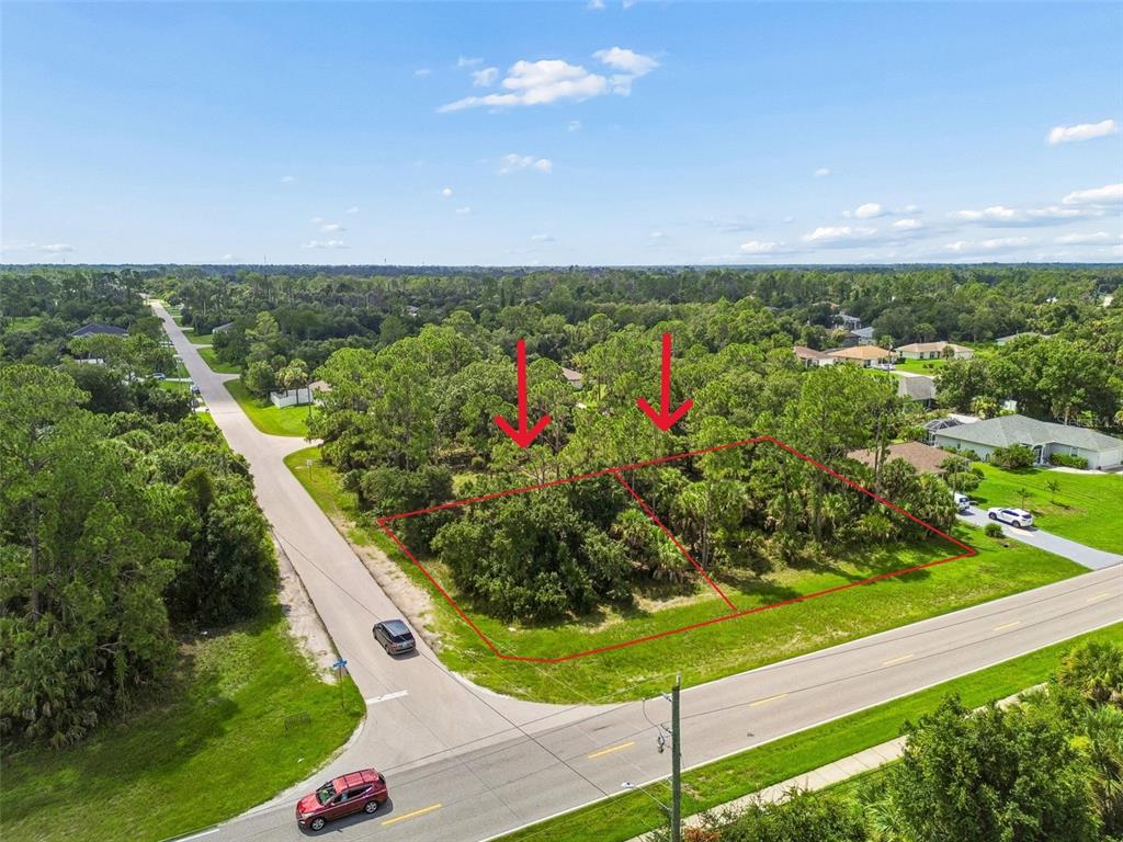 An aerial view shows two adjacent, wooded, undeveloped lots outlined in red near a road — 14 S CHAMBERLAIN BOULEVARD, NORTH PORT, FL