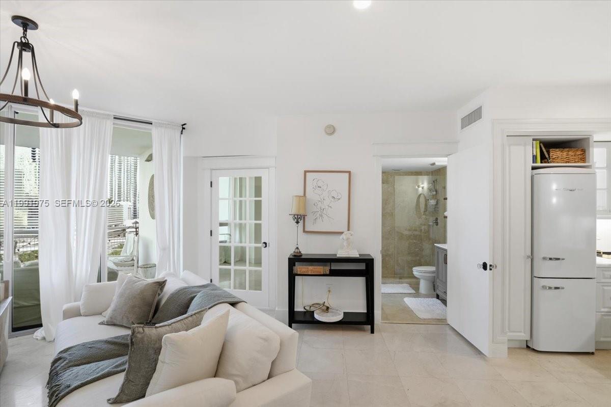 A bright living area features a white sofa, a black console table, and a refrigerator — 350 S Miami Ave # 1205, Miami FL 33130, MIAMI, FL