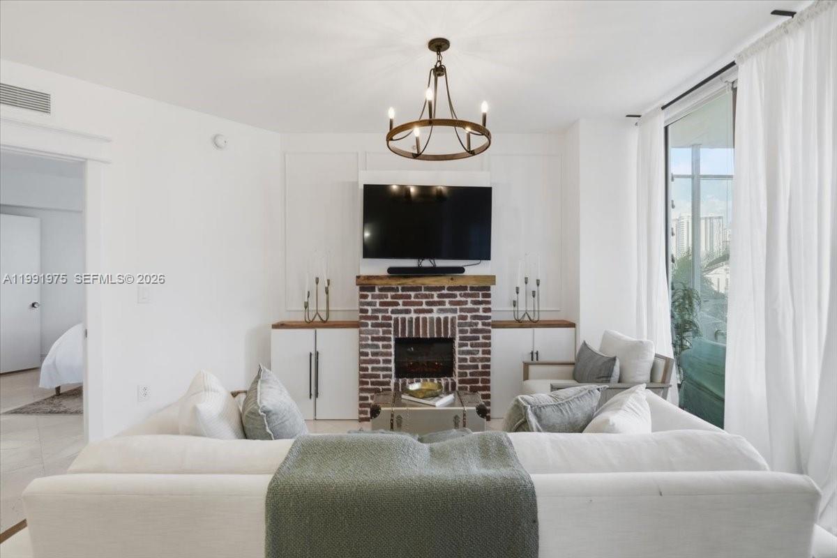 A living room features a brick fireplace, a wall-mounted television, and a white sofa — 350 S Miami Ave # 1205, Miami FL 33130, MIAMI, FL