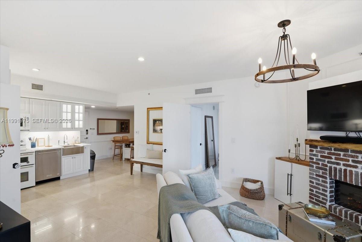 A bright living room features a brick fireplace, white cabinetry, and a modern chandelier — 350 S Miami Ave # 1205, Miami FL 33130, MIAMI, FL