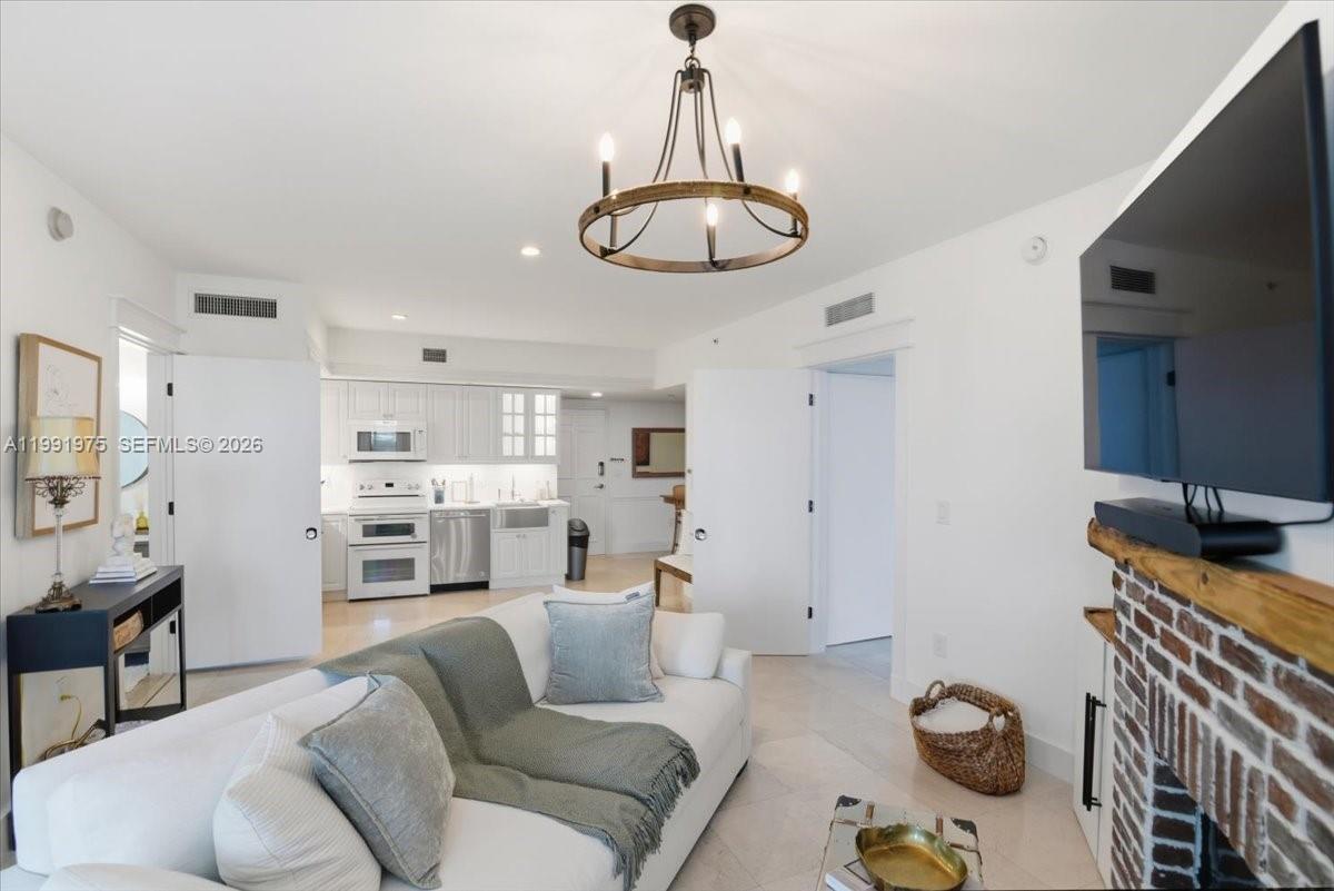 A living room features a white sofa, a brick fireplace, and an open kitchen — 350 S Miami Ave # 1205, Miami FL 33130, MIAMI, FL