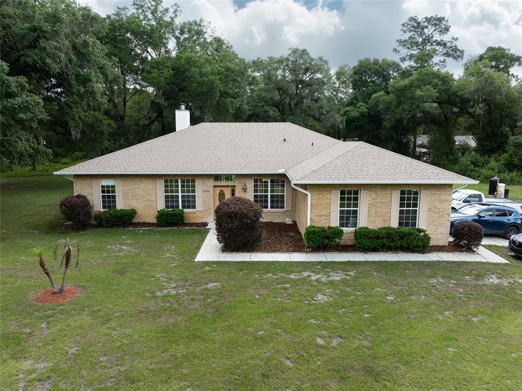 A single-story brick house with a hip roof sits on a grassy lot with trees — 2698 GOOD HOMES ROAD, DELAND, FL