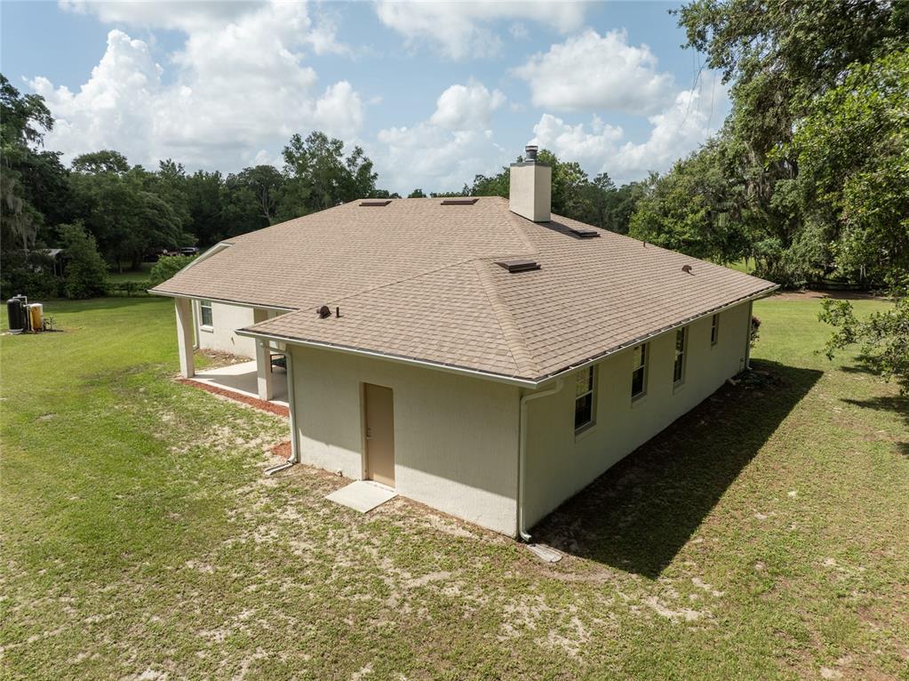An aerial view of a single-story house with a tan stucco exterior and shingled roof — 2698 GOOD HOMES ROAD, DELAND, FL