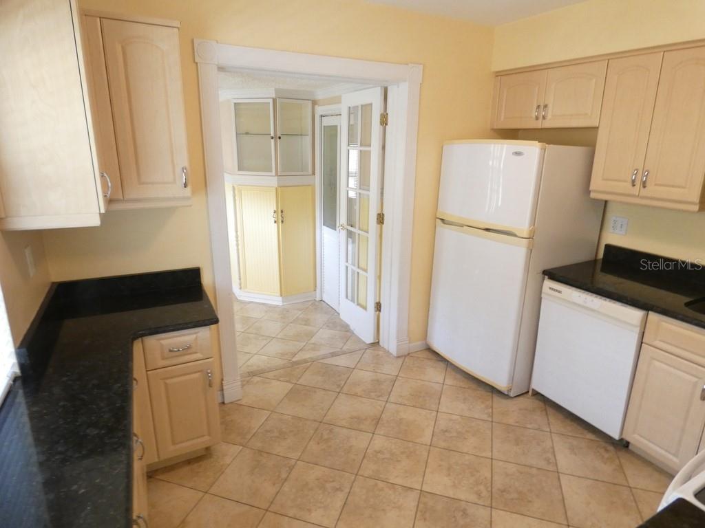 A kitchen with light wood cabinets, black countertops, white appliances, and beige tile flooring — 5220 11TH AVENUE N, ST PETERSBURG, FL