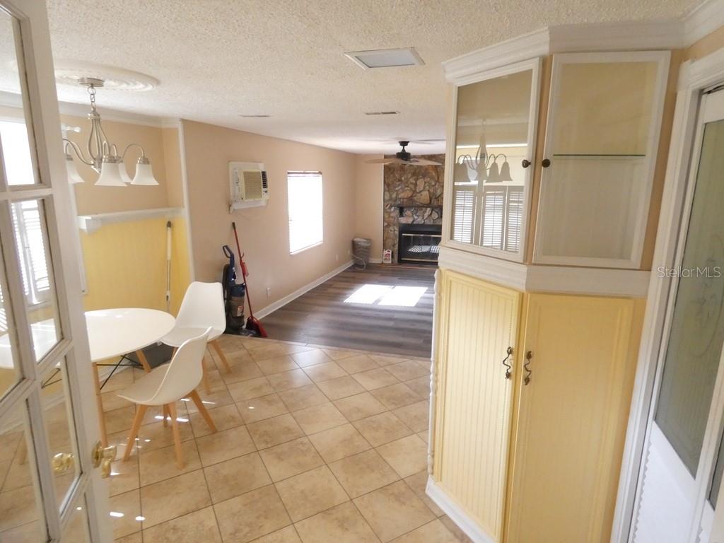 A dining area with tile floors leads into a living room featuring a stone fireplace — 5220 11TH AVENUE N, ST PETERSBURG, FL