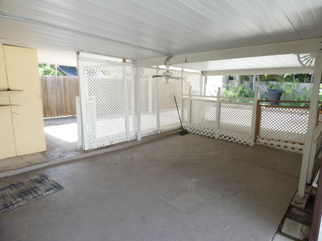 A covered concrete patio features white lattice privacy screens and a ceiling fan — 5220 11TH AVENUE N, ST PETERSBURG, FL
