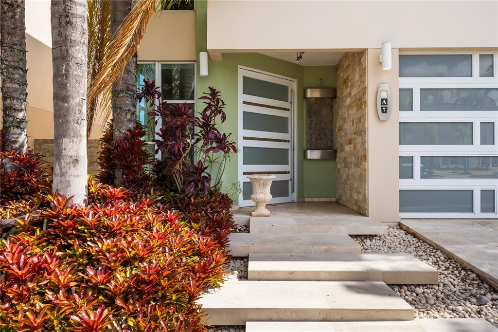 A modern home entrance features a light green wall, stone steps, and a glass-paneled door — Urb Mirabella Village CALLE NACAR UNIT A7, BAYAMON, PR