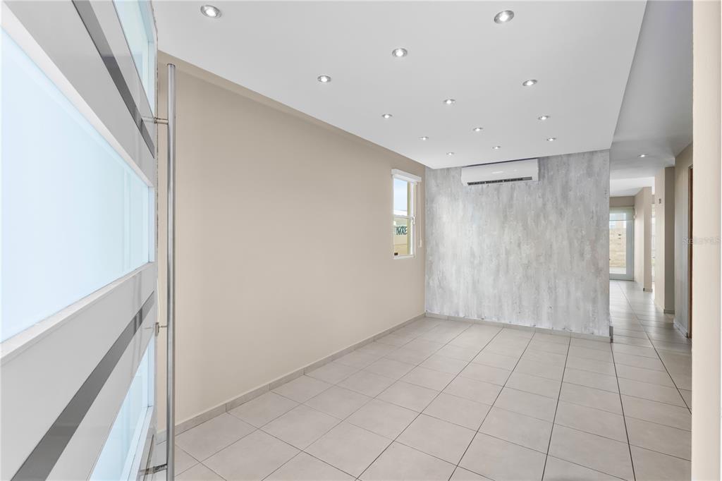 A modern room with light tile floors, recessed lighting, and a textured accent wall — Urb Mirabella Village CALLE NACAR UNIT A7, BAYAMON, PR