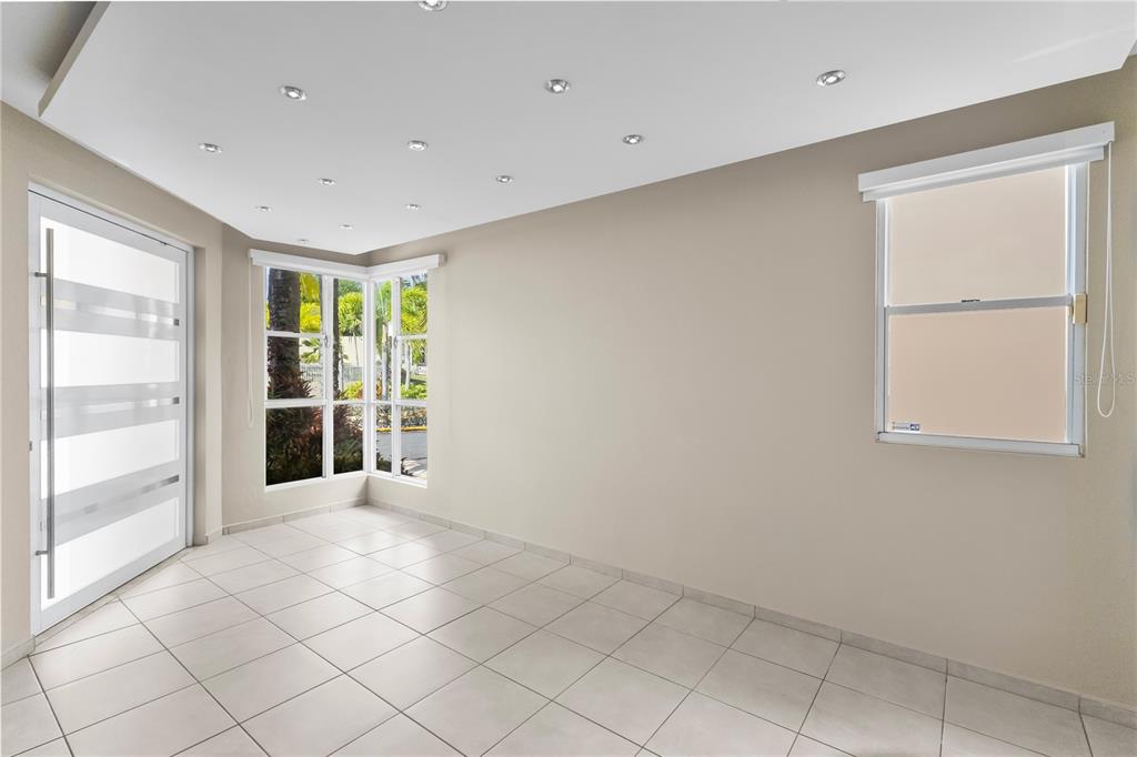 An empty room with light-colored tile floors, recessed ceiling lights, a corner window, and a door — Urb Mirabella Village CALLE NACAR UNIT A7, BAYAMON, PR