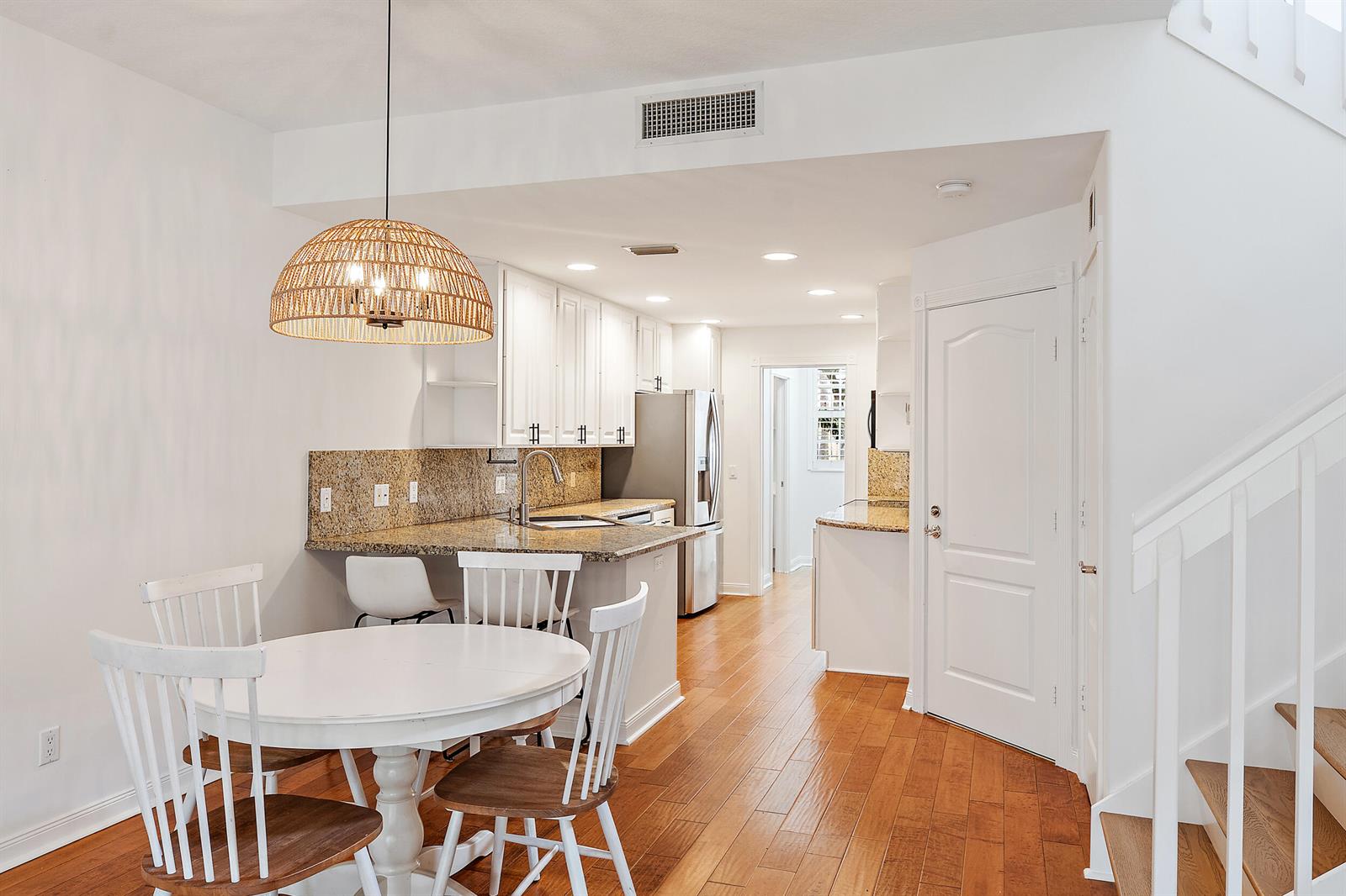 A dining area with a round table and a kitchen featuring white cabinets and granite — 442 Capistrano Drive, Palm Beach Gardens FL 33410, PALM BEACH GARDENS, FL