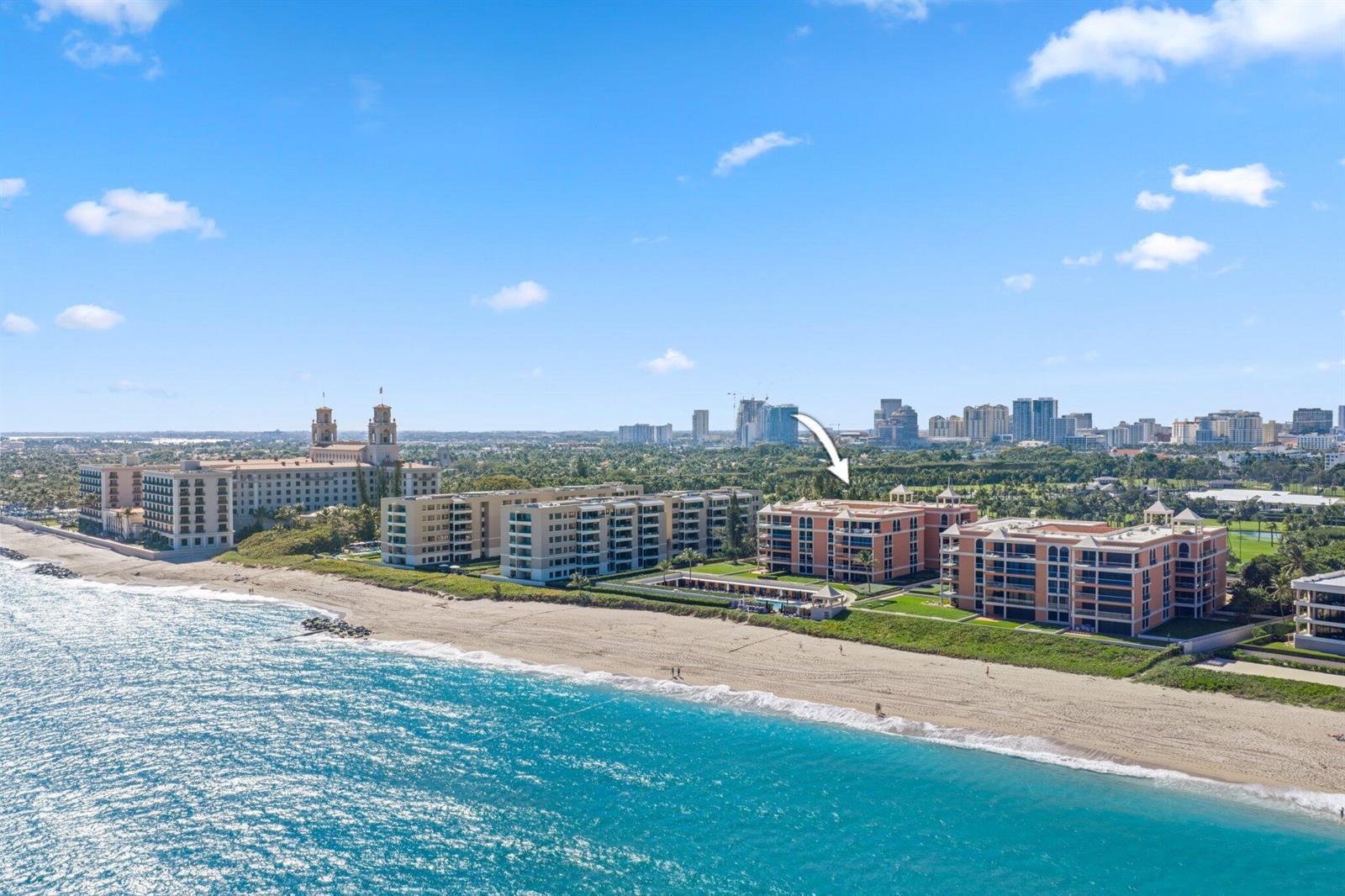 An aerial view of beachfront condominium buildings along the coast with a city skyline behind — 2 N Breakers Row # S32, Palm Beach FL 33480, PALM BEACH, FL