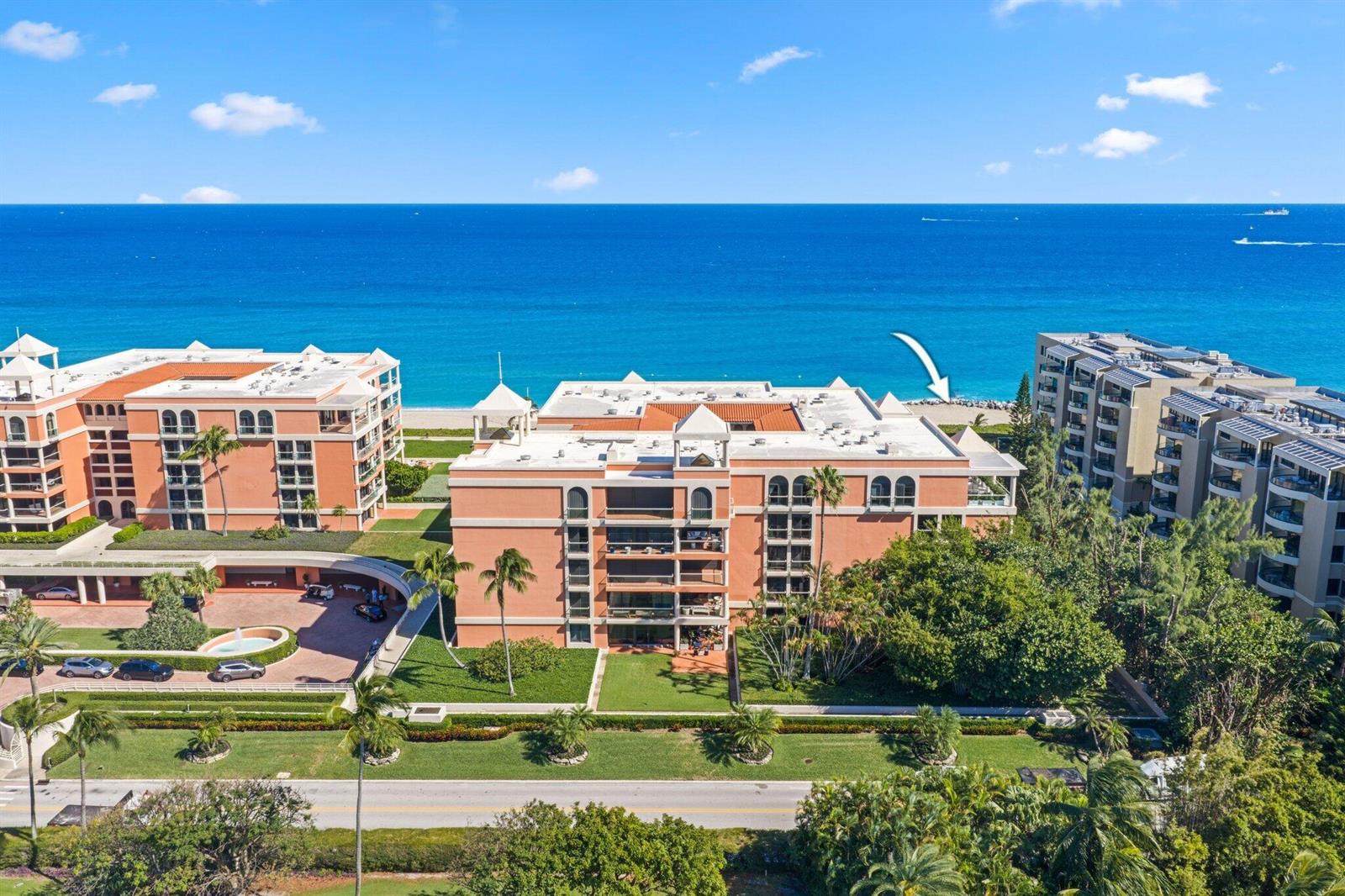 An aerial view shows two peach-colored beachfront condominium buildings surrounded by lush landscaping and trees — 2 N Breakers Row # S32, Palm Beach FL 33480, PALM BEACH, FL