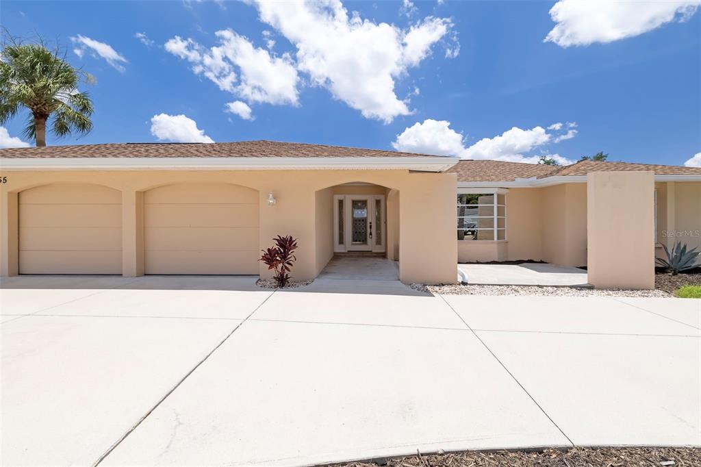 A beige single-story house features a two-car garage, a covered entryway, and a concrete driveway — 6755 AVENUE B, SARASOTA, FL