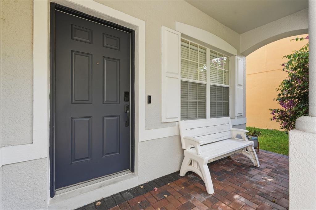 A dark gray front door sits next to a white bench on a brick porch — 8836 CAMERON CREST DRIVE, TAMPA, FL