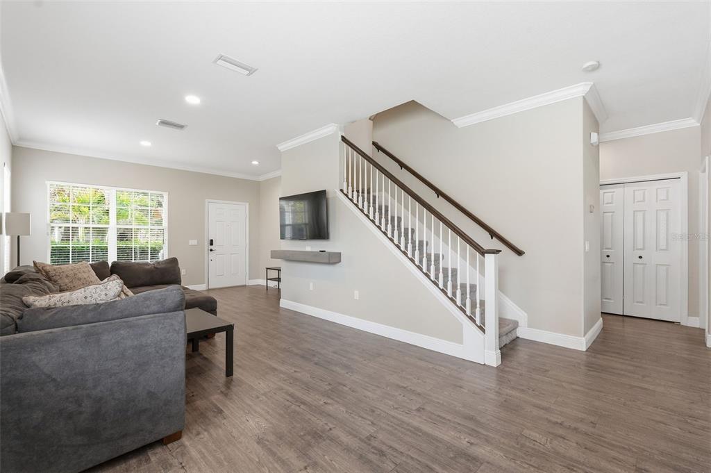 A living room features wood-look flooring, a gray sectional sofa, and a staircase with white railings — 8836 CAMERON CREST DRIVE, TAMPA, FL