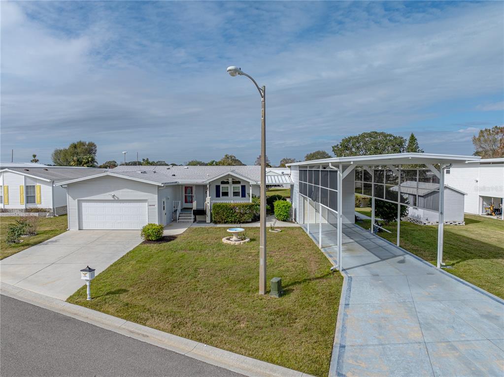 A single-story house with a garage, a screened carport, and a front lawn — 5148 ISLAND VIEW CIRCLE N, POLK CITY, FL