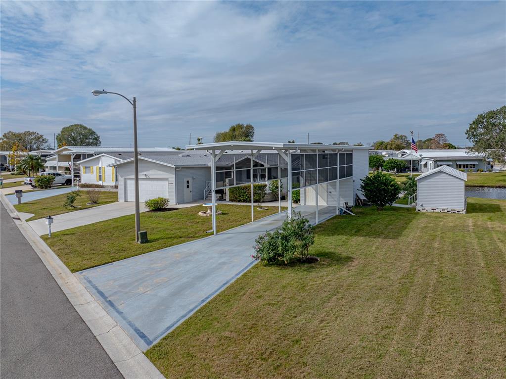 An exterior view of a manufactured home with a carport, driveway, and detached shed — 5148 ISLAND VIEW CIRCLE N, POLK CITY, FL