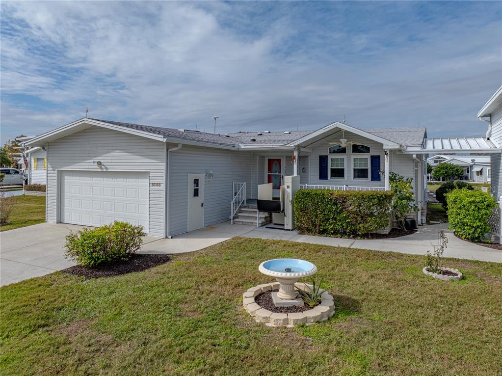 A light-gray single-story house features a garage, a front porch with a lift, and landscaping — 5148 ISLAND VIEW CIRCLE N, POLK CITY, FL
