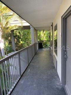 An outdoor walkway with a metal railing overlooks lush green trees — 7150 N TAMIAMI TRAIL UNIT S-604, SARASOTA, FL