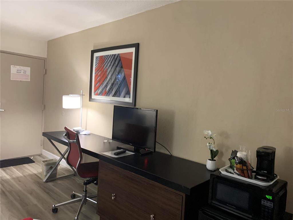 A hotel room features a desk with a television, a chair, and a microwave station — 7150 N TAMIAMI TRAIL UNIT S-604, SARASOTA, FL