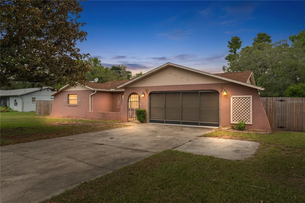 A pink single-story house with a brown roof, a garage, and a concrete driveway — 2354 DELTONA BOULEVARD, SPRING HILL, FL