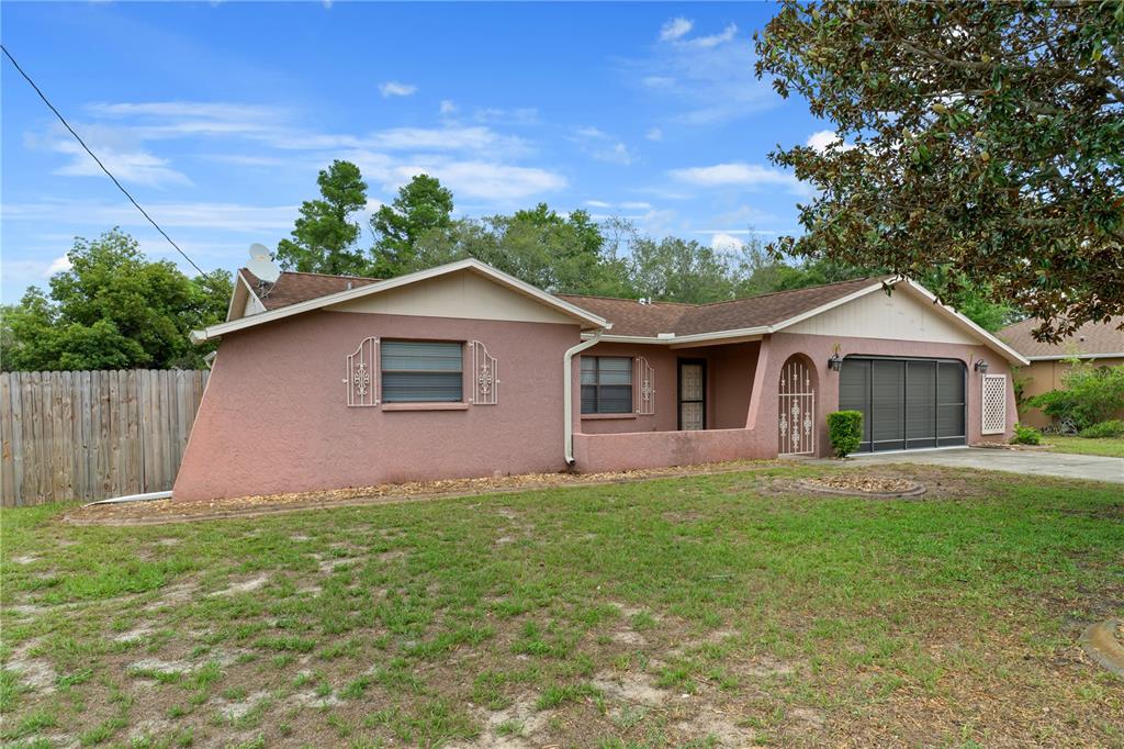 A single-story pink stucco house with a brown roof and a front-facing garage — 2354 DELTONA BOULEVARD, SPRING HILL, FL