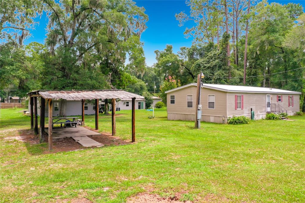 A mobile home sits on a grassy lot next to a covered outdoor picnic area — 1021 NW 111TH COURT, OCALA, FL
