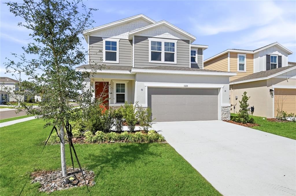 A two-story suburban house with a gray garage, light-colored siding, and a red front door — 5228 BEE BALM STREET, LAKE HAMILTON, FL