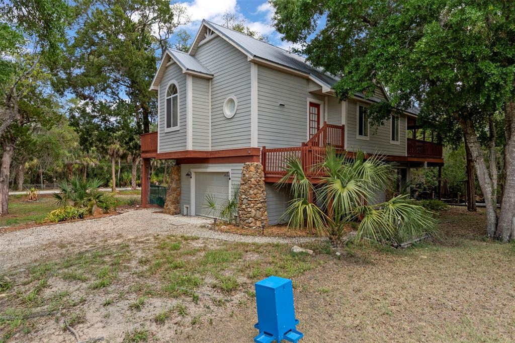 A two-story house with gray siding, a stone-accented garage, and a wooden deck — 6779 S PINEBRANCH POINT, HOMOSASSA, FL