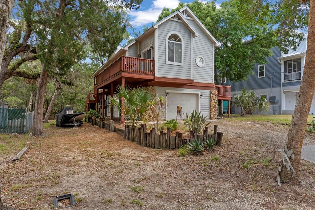 A two-story house with light gray siding, a wooden deck, and a ground-level garage — 6779 S PINEBRANCH POINT, HOMOSASSA, FL