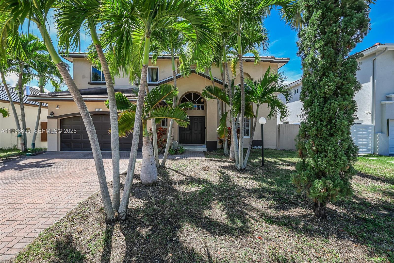 A two-story house with a paved driveway, palm trees, and a dark garage door — 14606 SW 158th Pl, Miami FL 33196, MIAMI, FL