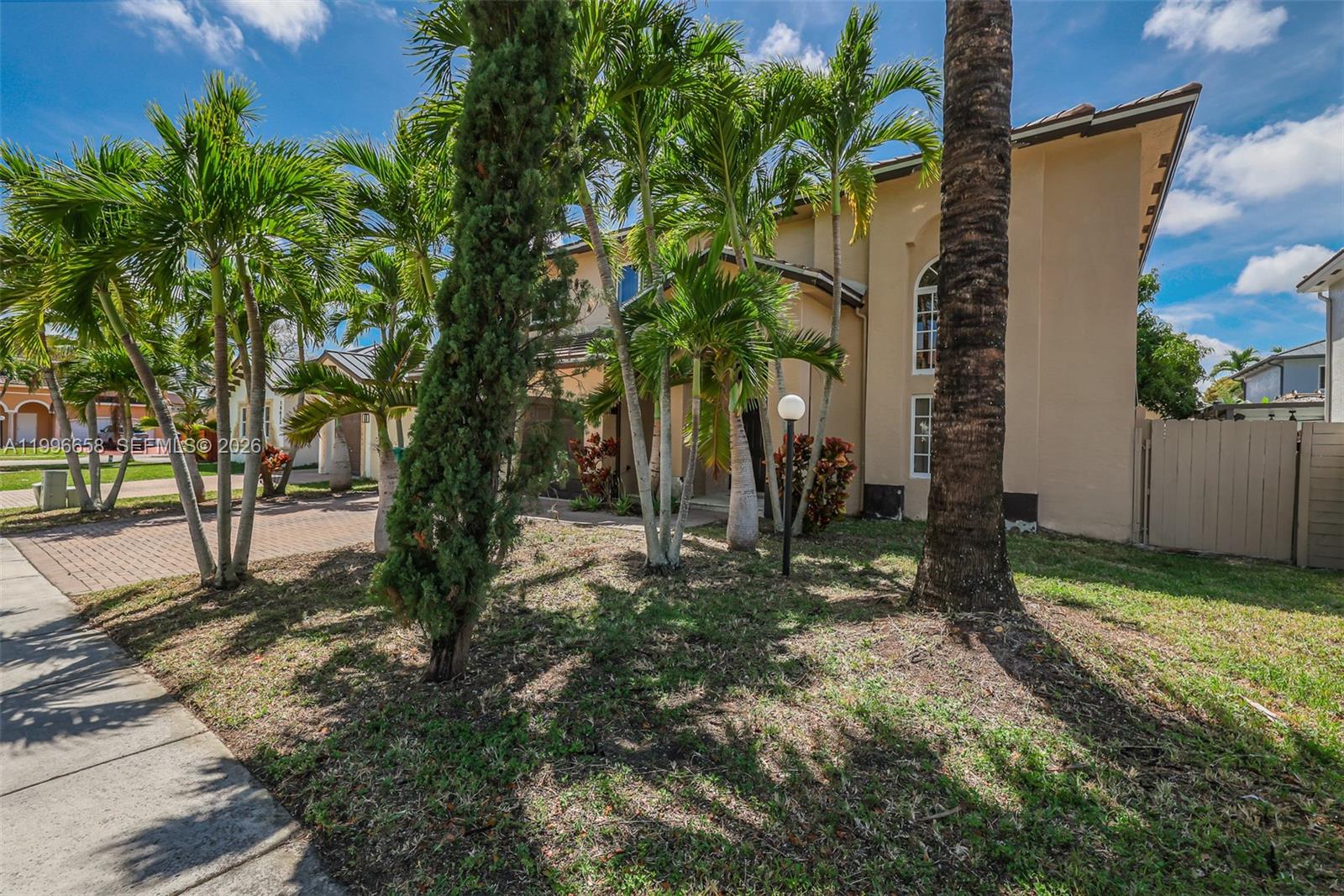 A two-story tan house features a paved driveway and several palm trees in the front yard — 14606 SW 158th Pl, Miami FL 33196, MIAMI, FL