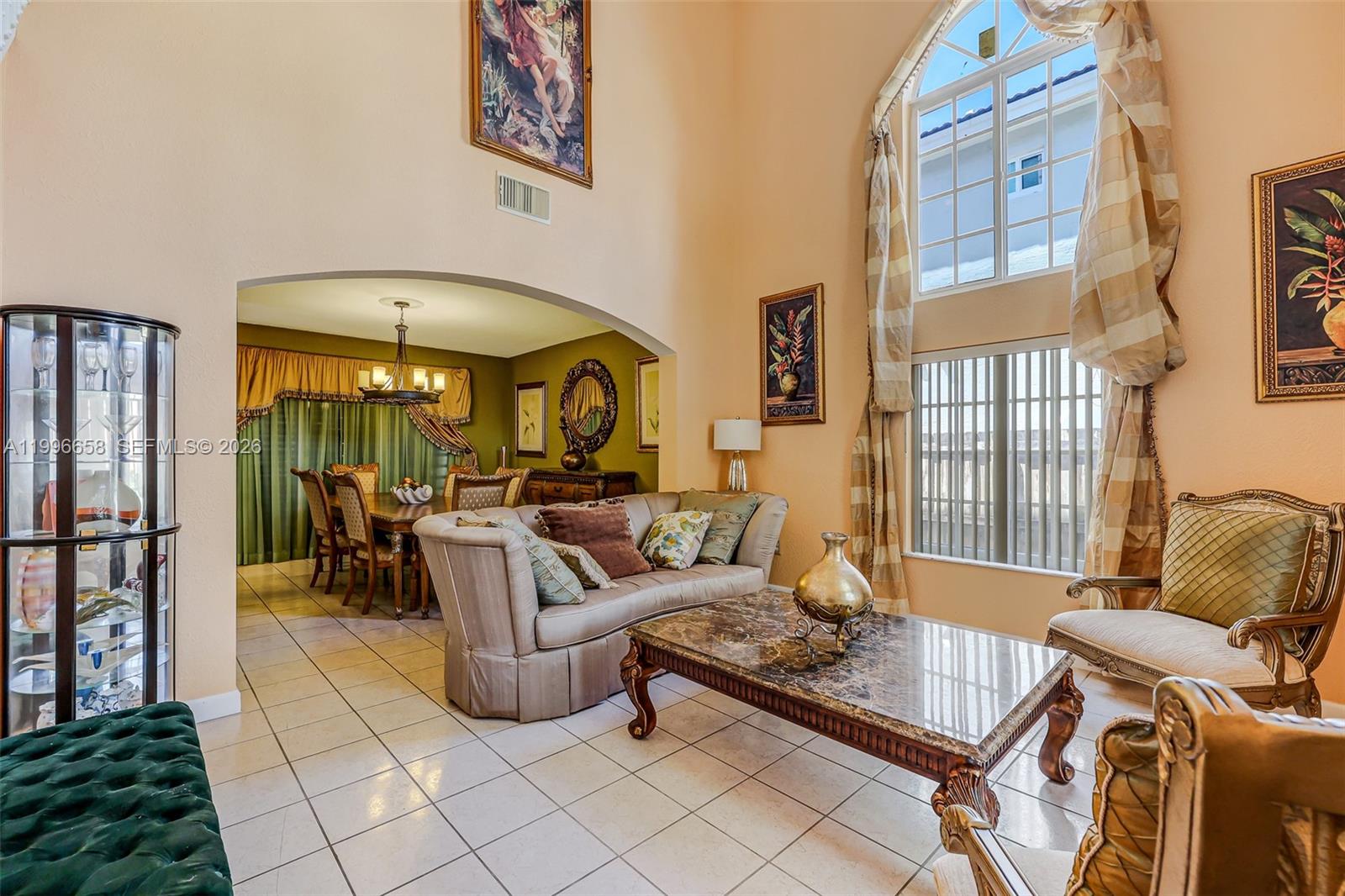 A living room with high ceilings, tile flooring, a marble coffee table, and an arched entryway — 14606 SW 158th Pl, Miami FL 33196, MIAMI, FL