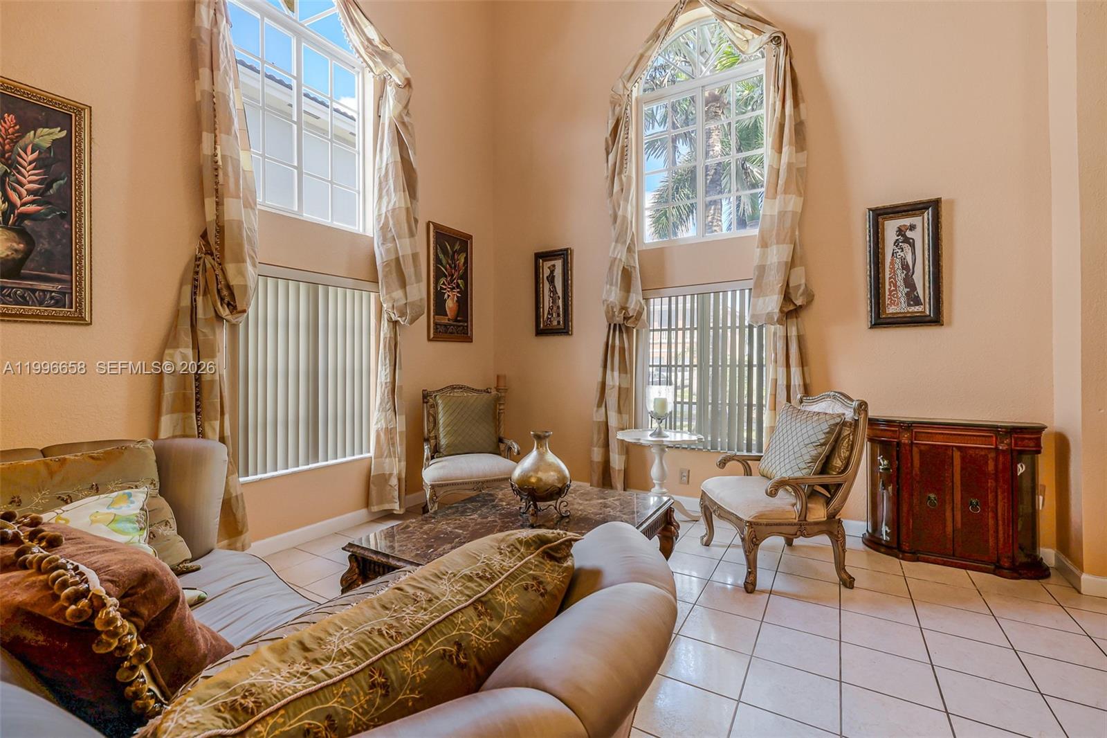 A living room with high ceilings, tall arched windows, tiled floors, and traditional furniture — 14606 SW 158th Pl, Miami FL 33196, MIAMI, FL