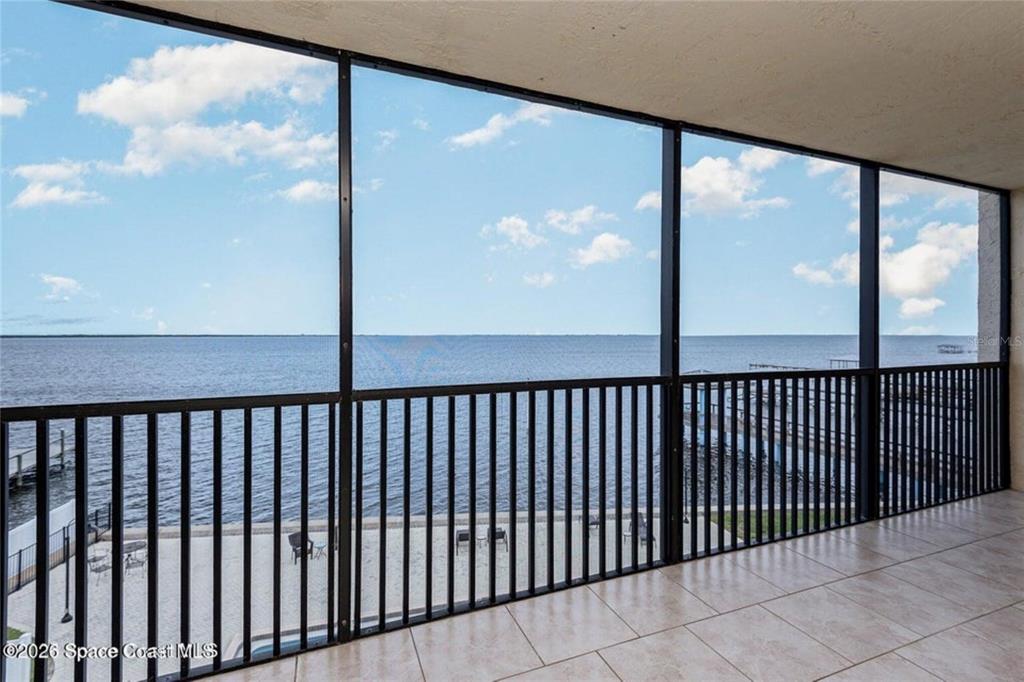 A screened-in balcony with tile flooring overlooks a large body of water — 525 INDIAN RIVER AVENUE UNIT 303, TITUSVILLE, FL
