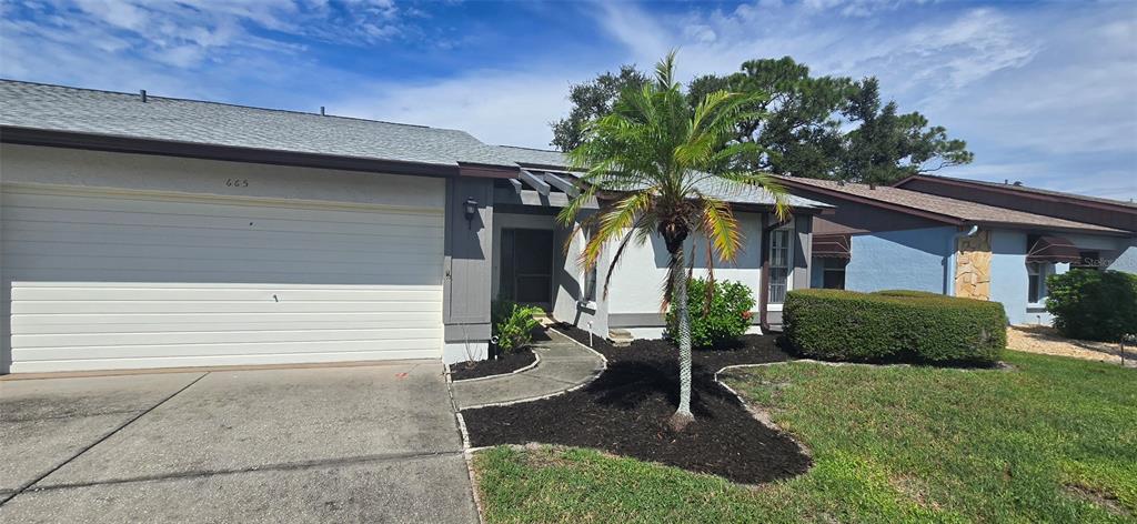 A single-story house features a two-car garage, a palm tree, and a landscaped front yard — 665 FOXWOOD BOULEVARD, ENGLEWOOD, FL